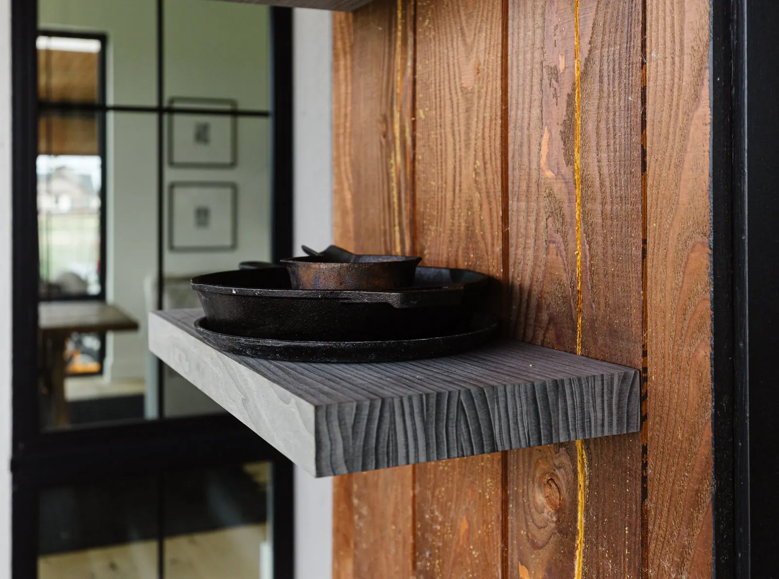 A charcoal textured floating shelf holding cast iron against a rough-sawn wood wall. Photo from ultrashelf.com.